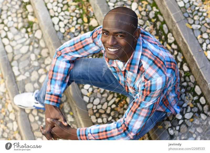 Schwarzer Mann lächelnd und sitzend in städtischen Stufen Glück schön Mensch maskulin Junger Mann Jugendliche Erwachsene 1 18-30 Jahre Straße Bekleidung Hemd