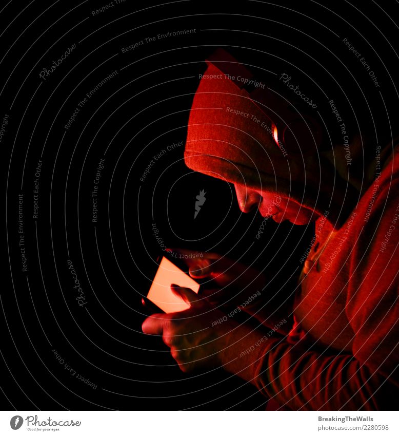 Mann im Hoodie, der Smartphone über schwarzem Hintergrund hält Lifestyle Freizeit & Hobby Spielen Computerspiel Entertainment Musik Handy Bildschirm