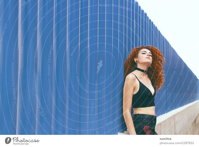 Junge Rothaarigefrau, die an einer blauen Wand sich lehnt Lifestyle elegant Stil schön Körper Haare & Frisuren Wellness Sinnesorgane Erholung Mensch feminin