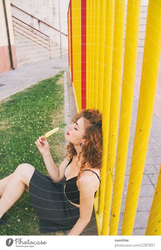 Junge Frau in einem Park, der eine ZitronenEiscreme genießt Lebensmittel Speiseeis Essen Lifestyle Stil Design Körper Haare & Frisuren Wellness Sinnesorgane
