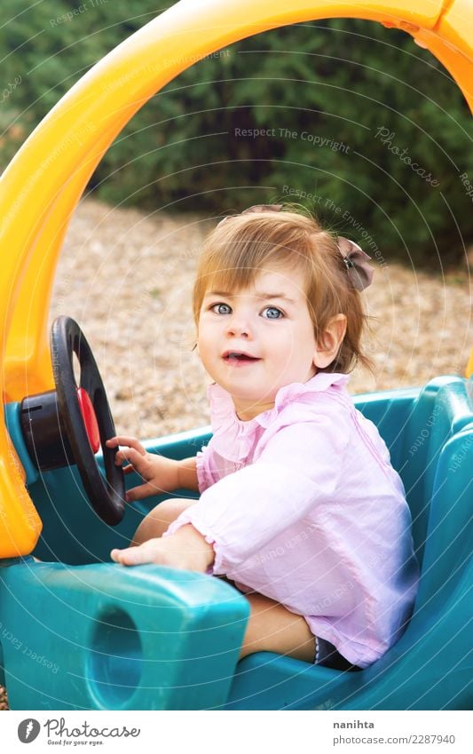 Glückliches kleines Mädchen spielt mit einem Spielzeugauto. Lifestyle Freude Wellness Wohlgefühl Spielen Kinderspiel Kindererziehung Schulhof Mensch feminin