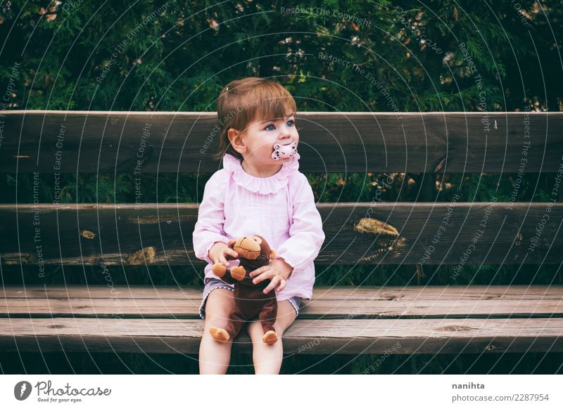 Reizendes kleines Mädchen, das in einer Holzbank sitzt Lifestyle Freude Wellness Erholung Freizeit & Hobby Kinderspiel Mensch feminin Kindheit 1 1-3 Jahre