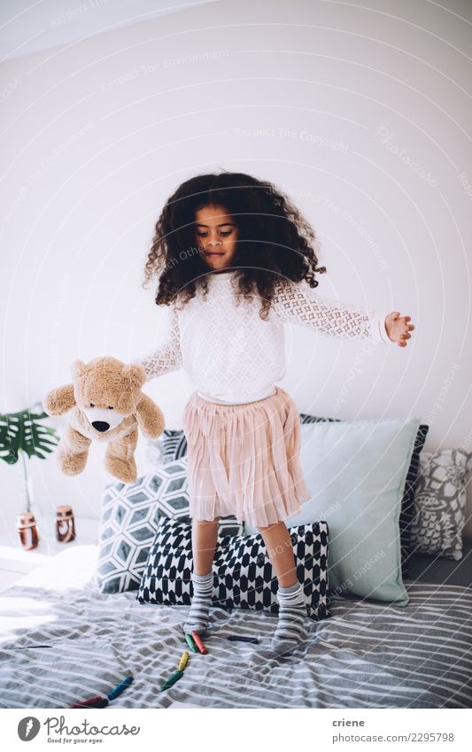 Kleines afrikanisches Mädchen, das auf Bett mit Teddybären springt Freude Glück schön Spielen Kind Mensch Kindheit Spielzeug lachen springen Fröhlichkeit klein