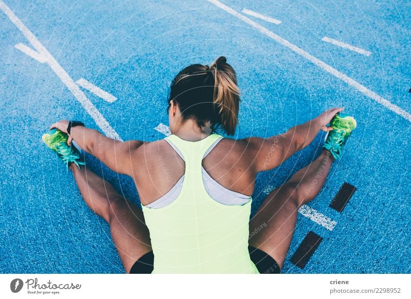 Fit Frau, die sich auf blauer Laufbahn vor dem Laufen dehnt. Lifestyle Sport Leichtathletik Erfolg Joggen Stadion Rennbahn Mensch Erwachsene Konkurrenz Beine