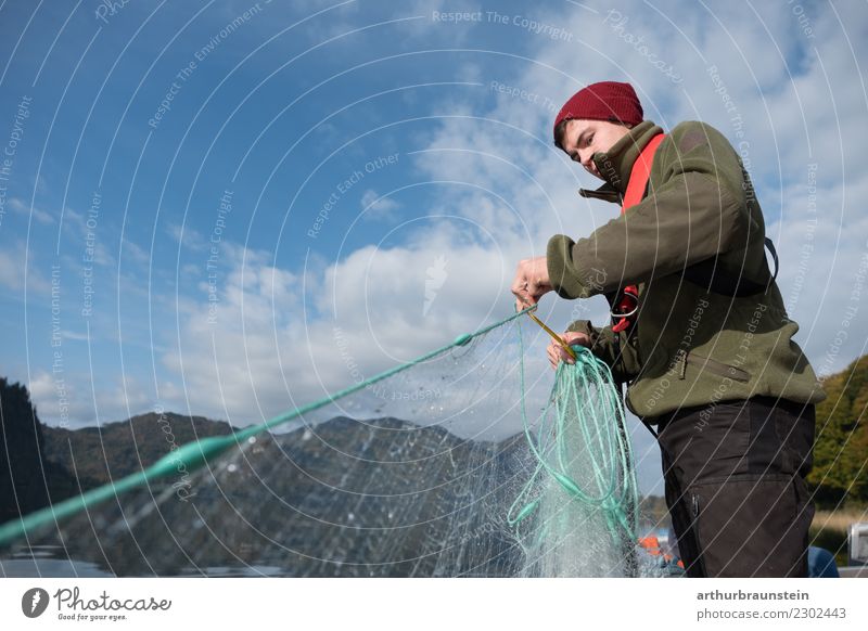 Junger Fischer holt sein Fischernetz ein jung Mann fischen See Wasser Fischfang blauer Himmel Hobby schönes Wetter sonnig Lehrberuf Azubi Beruf arbeiten