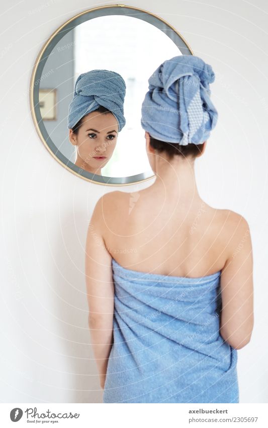 junge Frau in Handtuch gehüllt betrachtet sich im Spiegel Lifestyle schön Körperpflege Wellness Wohnung Schlafzimmer Bad Mensch feminin Junge Frau Jugendliche