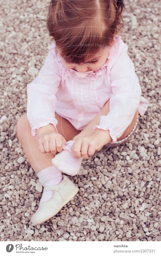Kleines Mädchen, das auf ihre Socken sich setzt Lifestyle Stil Kindererziehung Bildung Mensch feminin Kleinkind Kindheit 1 1-3 Jahre Mode Bekleidung Hemd