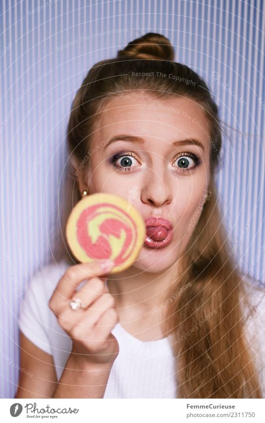 Young blonde woman showing a cookie feminin Junge Frau Jugendliche Erwachsene 1 Mensch 18-30 Jahre Freude rausstrecken Zunge Keks Mürbeplätzchen Süßwaren Zucker
