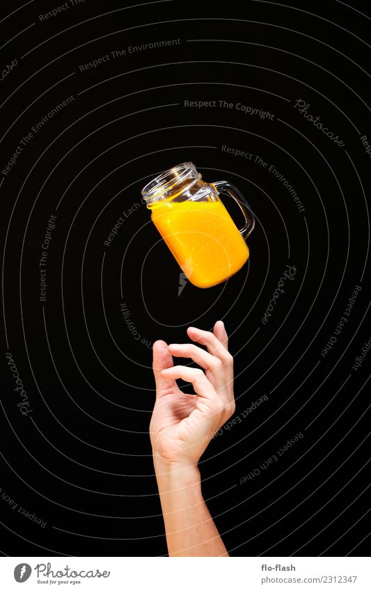EINE HAND GREIFT VON UNTEN NACH EINEM GLAS MIT GELBEN FLUID Lebensmittel Frucht Orange Frühstück Bioprodukte Vegetarische Ernährung Diät Fasten Getränk Limonade