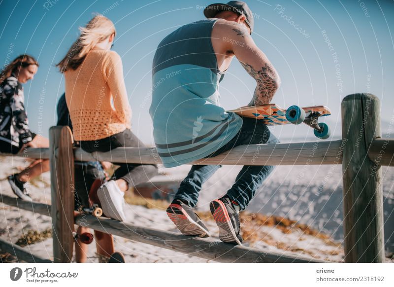 Gruppe von Freunden, die mit Skateboards am Strand herumhängen. Freude Leben Freizeit & Hobby Sommer Mensch Frau Erwachsene Mann Freundschaft Menschengruppe