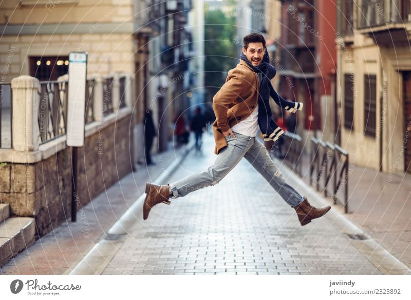 Glücklicher Mann beim Springen in Winterkleidung auf der Straße Stil Freude Mensch Junger Mann Jugendliche Erwachsene 1 18-30 Jahre Herbst Mode Bekleidung
