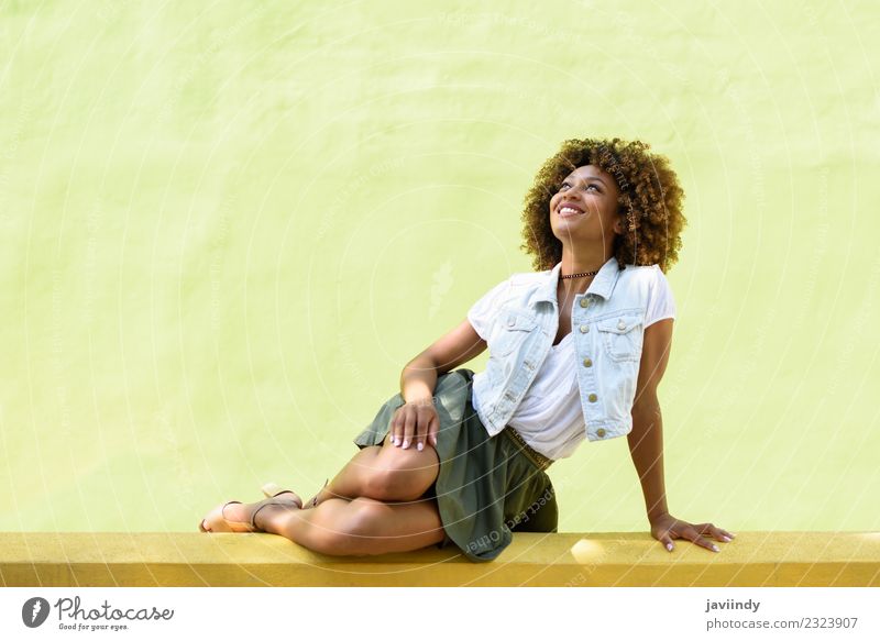 Junge schwarze Frau, Afrofrisur, sitzt lächelnd an einer Wand Lifestyle Stil Glück schön Haare & Frisuren Gesicht Mensch feminin Junge Frau Jugendliche