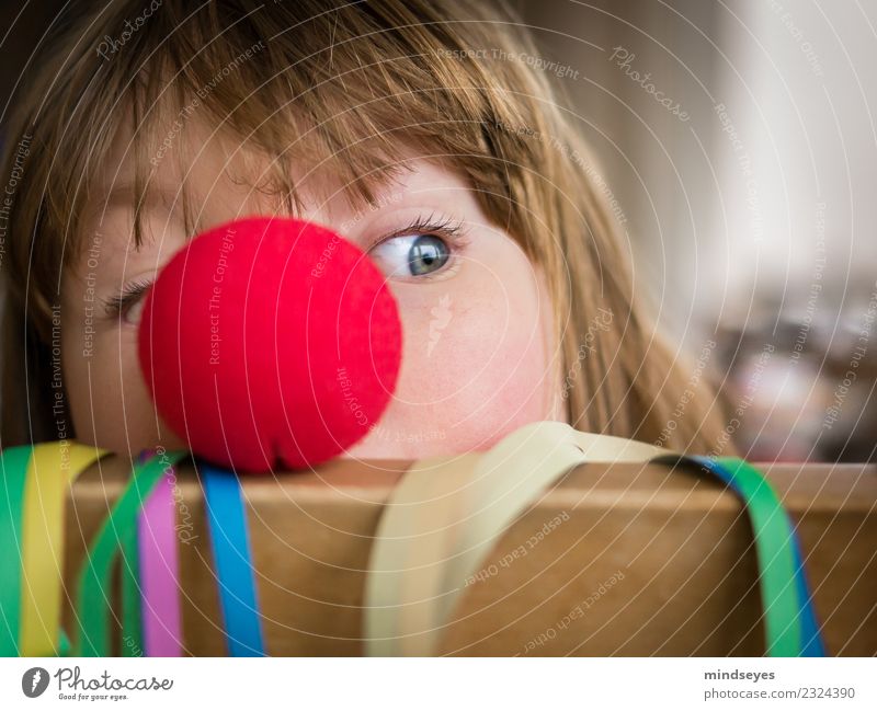 Blondes Mädchen schaut hinter roter Clownnase hervor. Freude Spielen Karneval Kindheit 1 Mensch 3-8 Jahre Zirkus Party Luftschlangen Nase Feste & Feiern frech