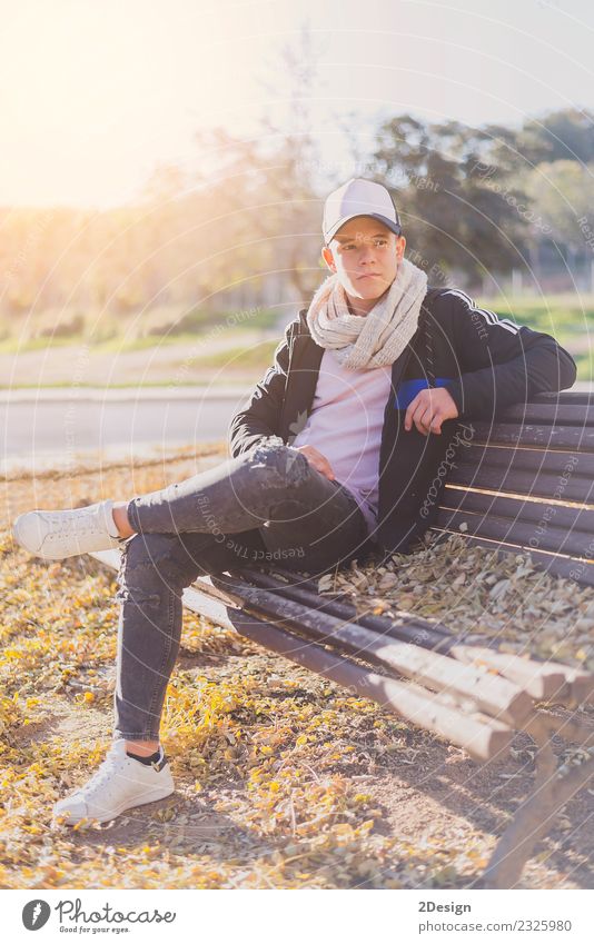 Stilvoller Teenager auf einer Holzbank sitzend Lifestyle Glück ruhig Schulkind Studium PDA Mensch Junge Mann Erwachsene Jugendliche Herbst Park Straße trendy
