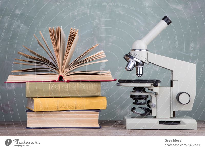 Bücher und Mikroskop auf dem Schreibtisch auf grünem Hintergrund Tisch Wissenschaften Schule lernen Klassenraum Studium Labor Buch Bibliothek schreiben Weisheit
