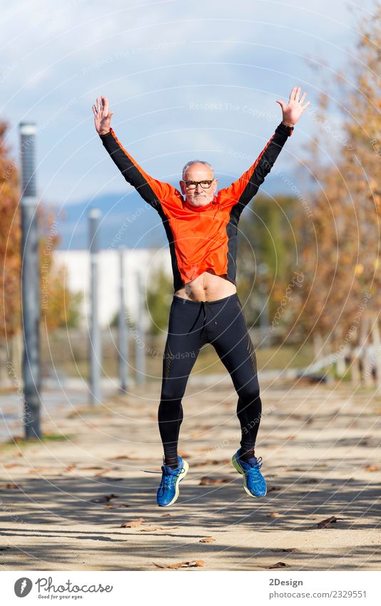 Senior Läufer Mann, der nach dem Laufen die Arme hochspringt. Lifestyle Freude Glück Körper Gesundheit Leben Freizeit & Hobby Sport Leichtathletik Sportler
