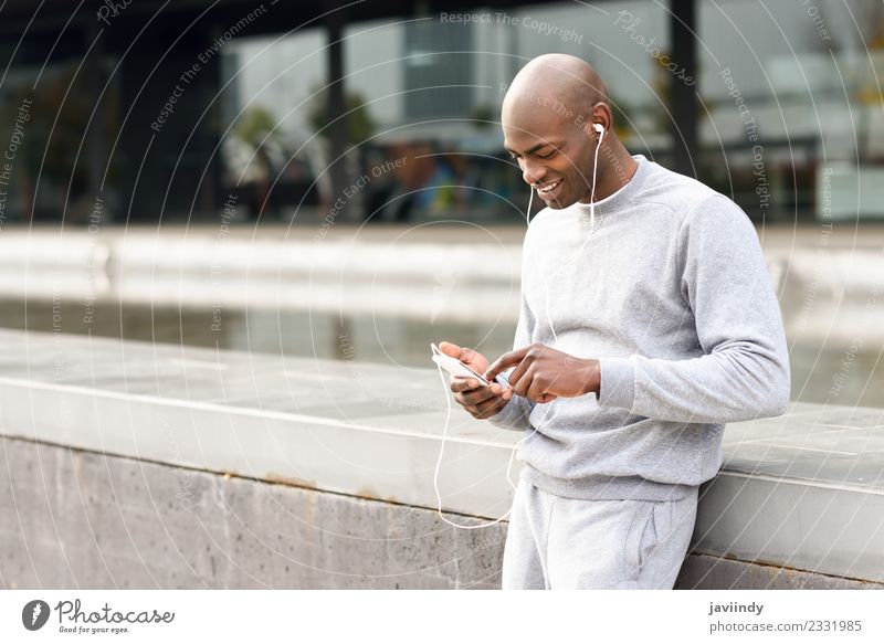 Attraktiver schwarzer Mann, der mit Kopfhörern im städtischen Hintergrund Musik hört Lifestyle Glück Sport Telefon PDA Technik & Technologie Mensch maskulin