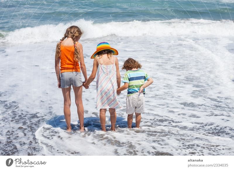 Drei glückliche Kinder spielen am Strand zur Tageszeit. Konzept der Sommerferien. Lifestyle Freude Glück schön Freizeit & Hobby Spielen Ferien & Urlaub & Reisen