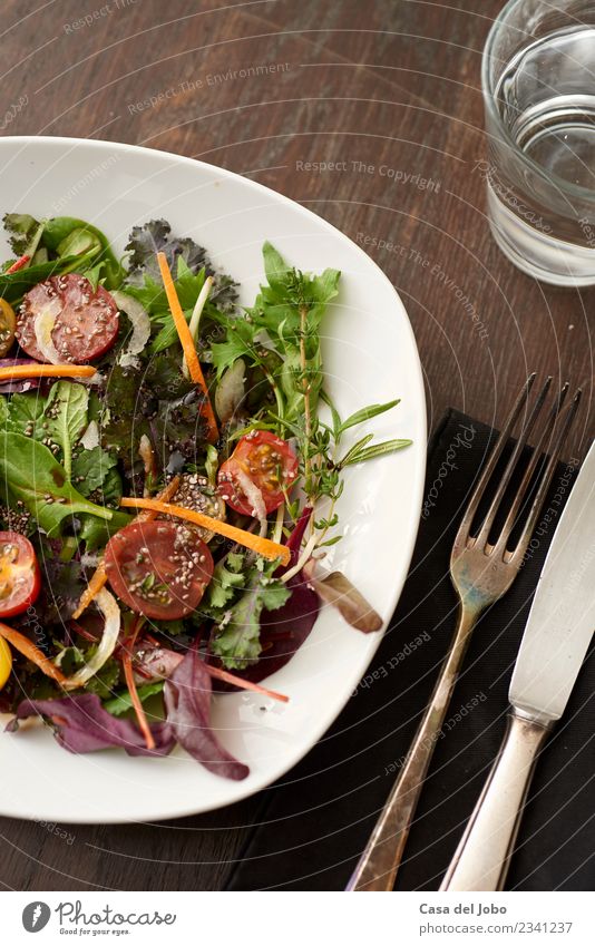 frischer Salat auf dunklem Holztisch Gemüse Ernährung Essen Mittagessen Abendessen Vegetarische Ernährung Diät Teller Glas Messer Gabel Lifestyle Übergewicht