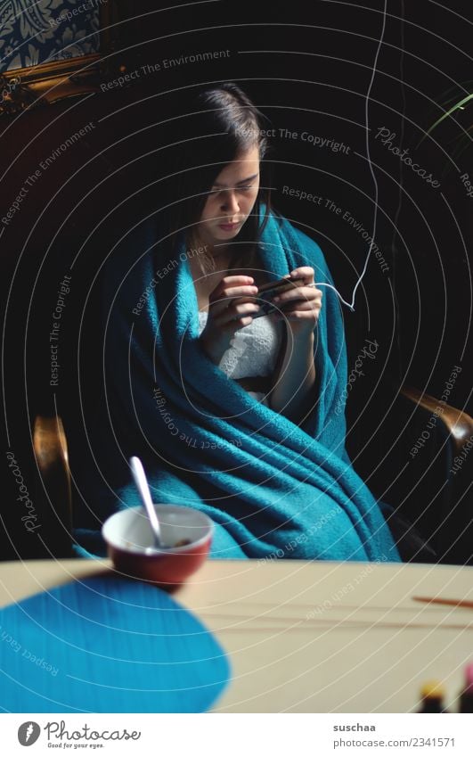 jugendliche sitzt in eine decke gehüllt am frühstückstisch und guckt in ihr smartphone Mädchen Kind Jugendliche Junge Frau 13-18 Jahre Internet Telefon SMS