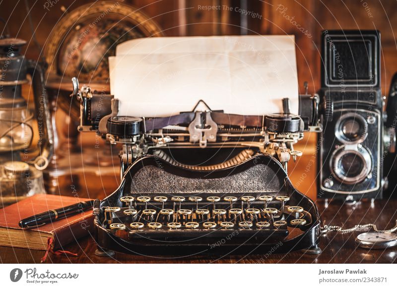 Vintage-Fotografiestilleben mit Schreibmaschine, Faltkamera, Weltkarte und Buch auf einem Holztisch. weiß gealtert Antiquität Hintergrund schwarz braun Business