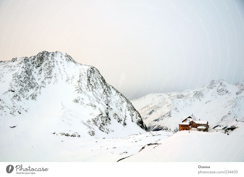 Haus in den Bergen Berge u. Gebirge Felsen Gipfel Schneebedeckte Gipfel Bergkamm Alpen Winter weiß kalt Himmel Dämmerung Hütte Schutzhütte Monochrom karg Ziel