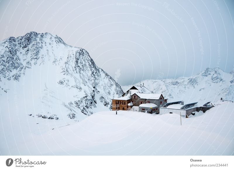 Haus in den Bergen Berge u. Gebirge Felsen Gipfel Schneebedeckte Gipfel Bergkamm Alpen Winter weiß kalt Himmel Dämmerung Hütte Monochrom karg Bergsteigen Ziel