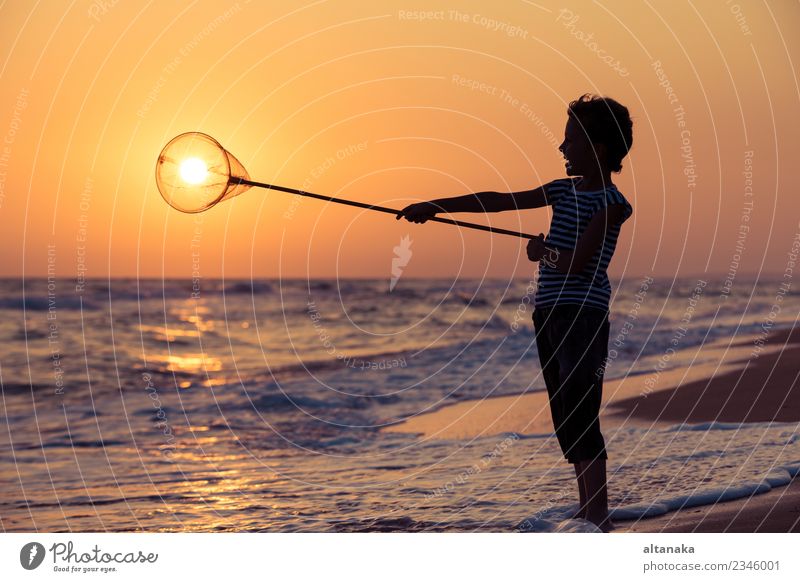 Ein glücklicher kleiner Junge, der zur Sonnenuntergangszeit am Strand spielt. Lifestyle Freude Glück schön Erholung Freizeit & Hobby Spielen