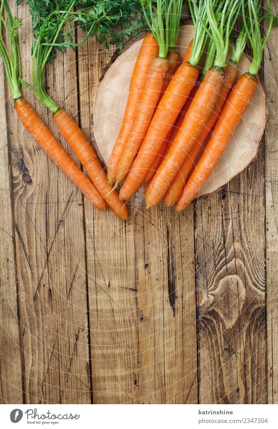 Frische rohe Karotten mit Blättern auf einem Holztisch Gemüse Ernährung Vegetarische Ernährung Blatt frisch braun grün Möhre Landwirt Lebensmittel Ernte