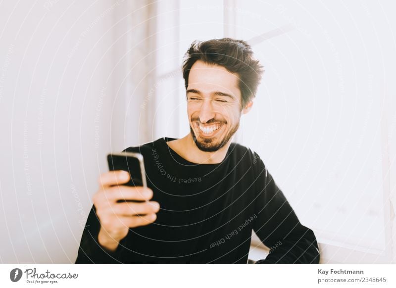 Junger Mann liest Textnachricht auf seinem Handy Lifestyle Reichtum Freude Glück Sommer Häusliches Leben Wohnung Kapitalwirtschaft Funktelefon maskulin