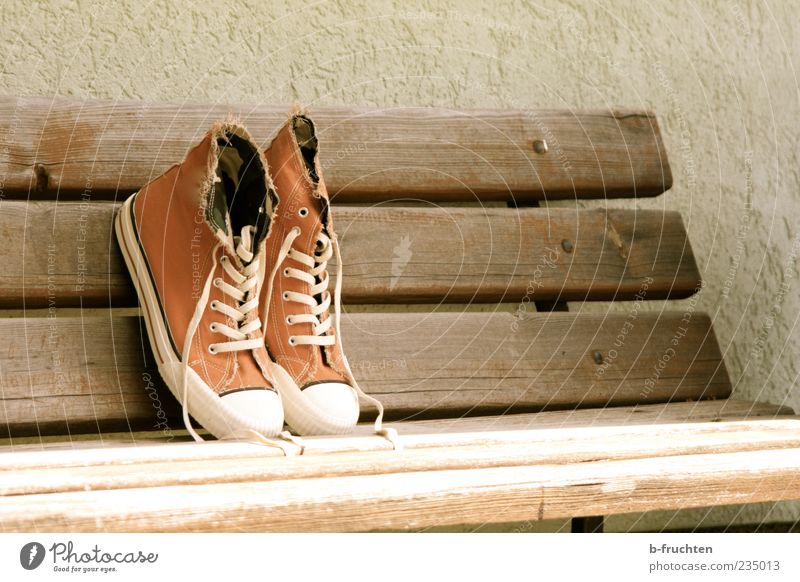 Stoffschuhe auf einer Parkbank, Antik-Look Design Mauer Wand Schuhe Turnschuh Holz alt dreckig braun Einsamkeit schnürschuh Farbfoto Außenaufnahme Menschenleer