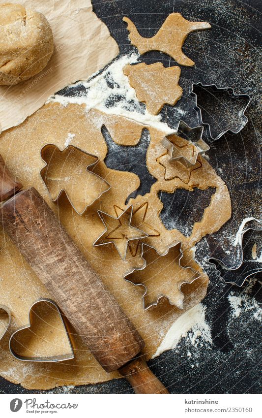 Weihnachtskekse mit Keksausstechern auf einem dunklen Tisch zubereiten. Teigwaren Backwaren Dessert Winter Küche Metall machen braun weiß Tradition backen