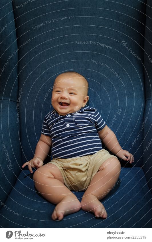 ein glücklicher kleiner Junge, der auf einem Sofa sitzt und lächelt. Lifestyle Freude Glück schön Freizeit & Hobby Wohnzimmer Kind Mensch Baby Kleinkind