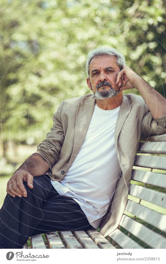 Nachdenklicher reifer Mann, der auf einer Bank in einem Stadtpark sitzt. Lifestyle Glück Ruhestand Mensch Erwachsene Männlicher Senior 1 45-60 Jahre