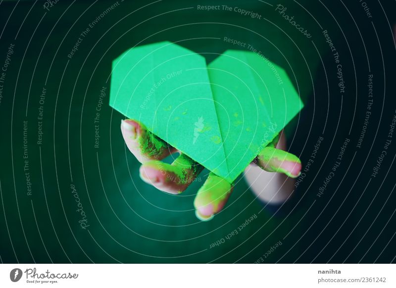 Hand hält ein grünes Papierherz. Design exotisch Handarbeit Origami Kunst Künstler bemalt Farben und Lacke Farbpulver Zeichen Herz dreckig dunkel authentisch