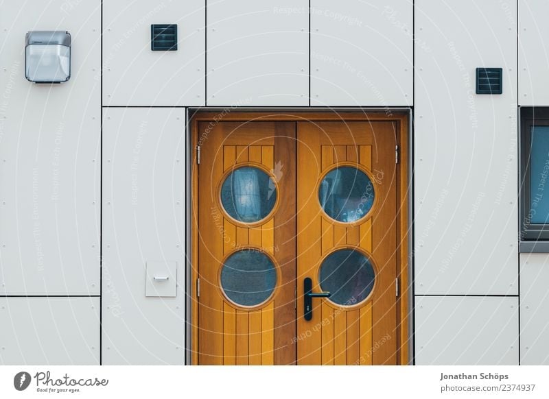 Tür mit runden Fenstern an weißer Fassade Holztür Haustür Außentür runde fenster Guckloch braun modern Hafen maritim minimalistisch geometrisch Architektur haus