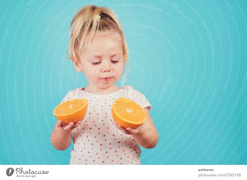 Baby isst eine Orange auf blauem Hintergrund Lebensmittel Frucht orange Ernährung Essen Mittagessen Lifestyle Freude Gesunde Ernährung Mensch feminin Mädchen