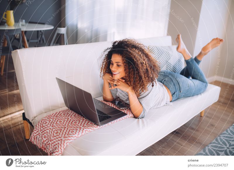 afrikanische glückliche Frau auf der Couch liegend mit Laptop Lifestyle Glück schön Erholung Sofa Arbeit & Erwerbstätigkeit Computer Notebook