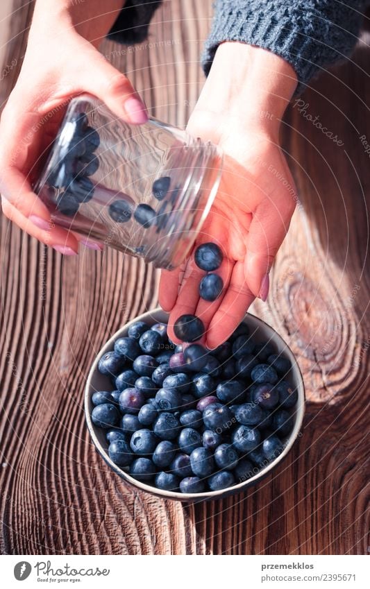 Frau, die frische Heidelbeeren aus einem Glas in eine kleine Schüssel legt. Lebensmittel Frucht Ernährung Bioprodukte Vegetarische Ernährung Diät