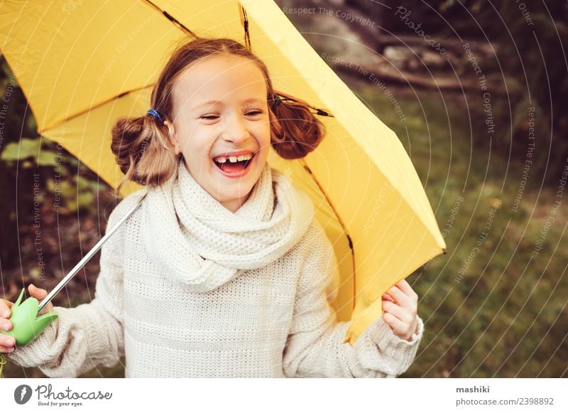 glückliches Kind Mädchen, das sich unter dem Regenschirm versteckt. Lifestyle Freude Glück Spielen stricken Garten Kindheit Natur Herbst Wetter Park Pullover