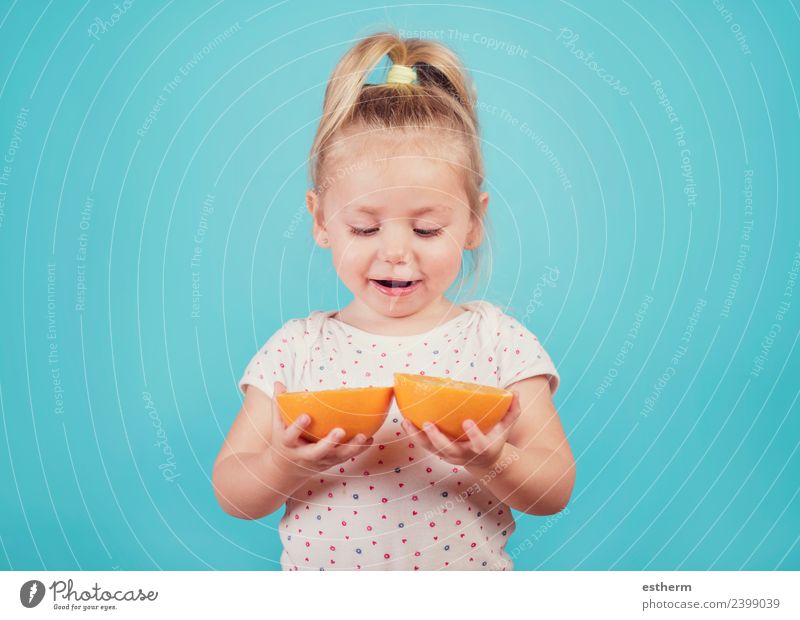 lächelndes Baby mit einer Orange auf blauem Hintergrund Lebensmittel Frucht Ernährung Essen Lifestyle Freude Wellness Mensch feminin Mädchen Kindheit 1
