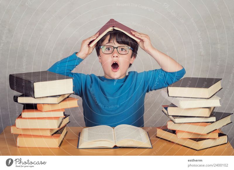 überraschter Junge mit Büchern auf einem Tisch Lifestyle Freude lesen Mensch maskulin Kind Kleinkind Kindheit 1 8-13 Jahre Kultur Bewegung Denken festhalten