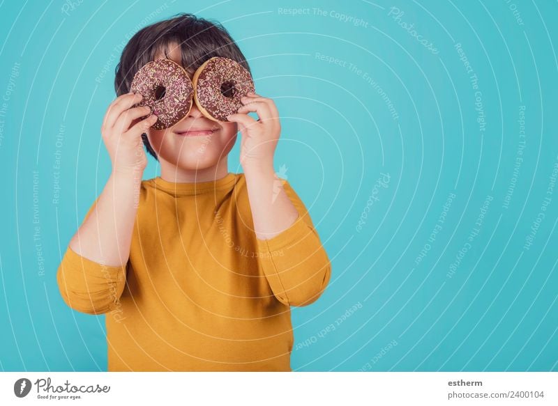 lächelnder Junge hält Donuts über ihre Augen. Lebensmittel Brötchen Ernährung Frühstück Mittagessen Lifestyle Mensch maskulin Kind Kleinkind Kindheit 1