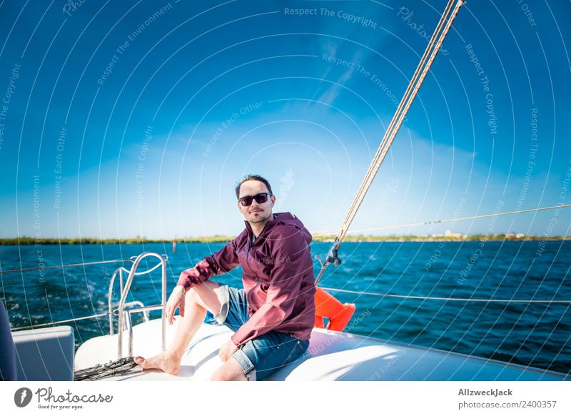 junger Mann sitzt auf einem Segelboot auf dem Meer Tag 1 Mensch Porträt Junger Mann Kurzhaarschnitt Sonnenbrille Wasser Segeln maritim See Blauer Himmel