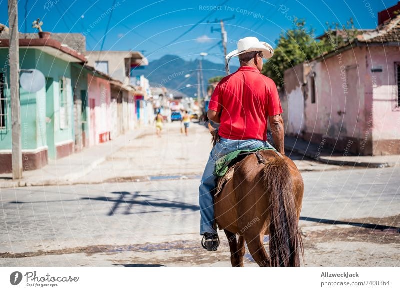 Mann auf einem Pferd reitet durch Trinidad in Kuba Sozialismus alt historisch retro old-school altmodisch Außenaufnahme Tag Sommer Sonne Blauer Himmel Wärme