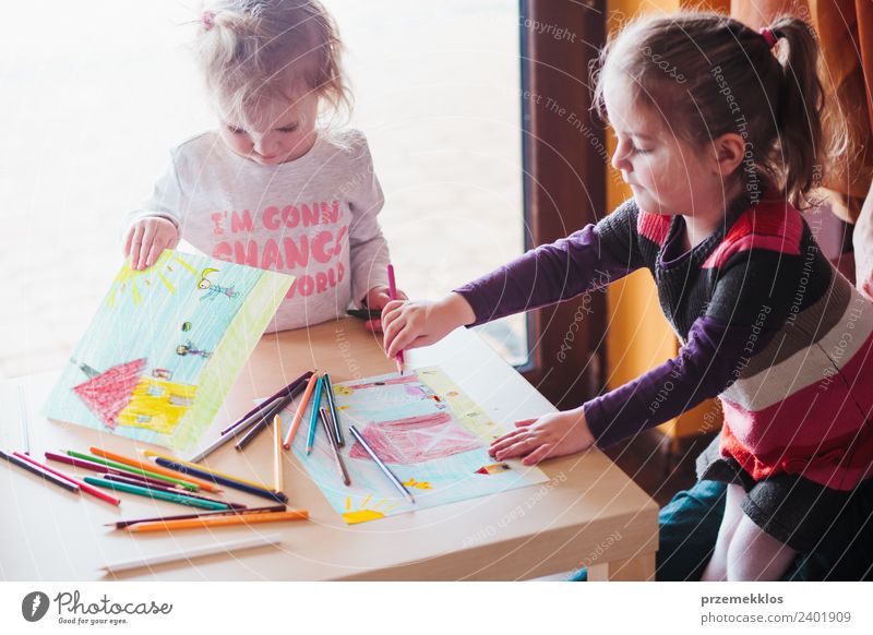 Zwei kleine Mädchen, die die bunten Bilder zeichnen. Lifestyle Freude Glück Handarbeit Tisch Bildung Kindergarten Schule Handwerk Mensch Schwester