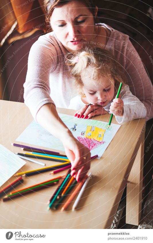 Mama mit kleiner Tochter, die die bunten Bilder zeichnet. Lifestyle Freude Glück Handarbeit Tisch Kindergarten Schule Mensch Mädchen Frau Erwachsene Eltern