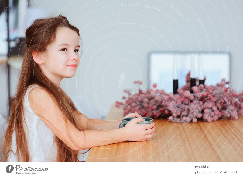 glückliches 5 Jahre altes Kind Mädchen beim Frühstück zu Hause Ernährung Kakao Tee Lifestyle Glück Tisch Küche Kindheit Lächeln sitzen authentisch heiß modern