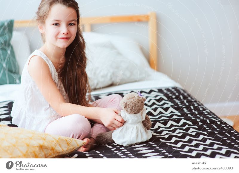 süßes glückliches Kind Mädchen entspannend zu Hause auf dem Bett Lifestyle Freude Erholung Schlafzimmer Spielzeug Teddybär Lächeln schlafen träumen klein lustig