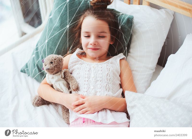 süßes kleines Kind Mädchen schläft in einem bequemen Bett. Lifestyle Freude Erholung Schlafzimmer Spielzeug Teddybär Lächeln schlafen träumen lustig niedlich
